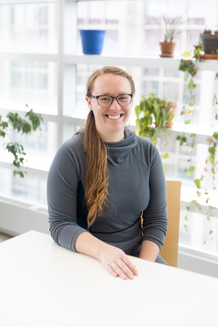 Smiling woman seated at table with house plants in the background