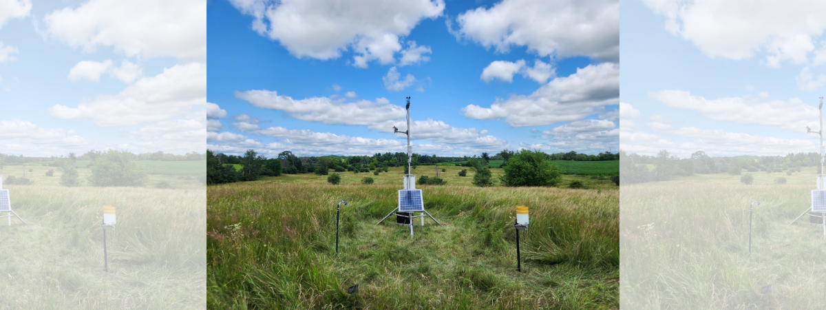 Image of a weather station in a field on a partly cloudy day.