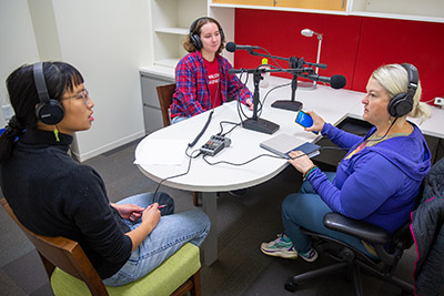Three women having a discussion around a table during a podcast recording