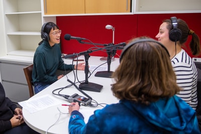 Four women having a discussion around a table during a podcast recording