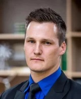 Headshot of Jarrad Wright in a black suit with a blue shirt.