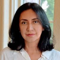 Headshot of Cristina Carvajal with a slight grin wearing a white shirt