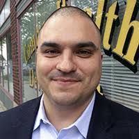 Headshot of Justice Castaneda with a slight grin wearing a white shirt