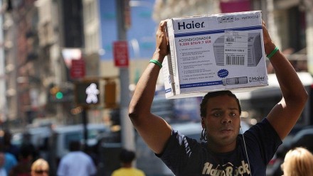 image captionA man carrying an air conditioner during a hot spell in New York
