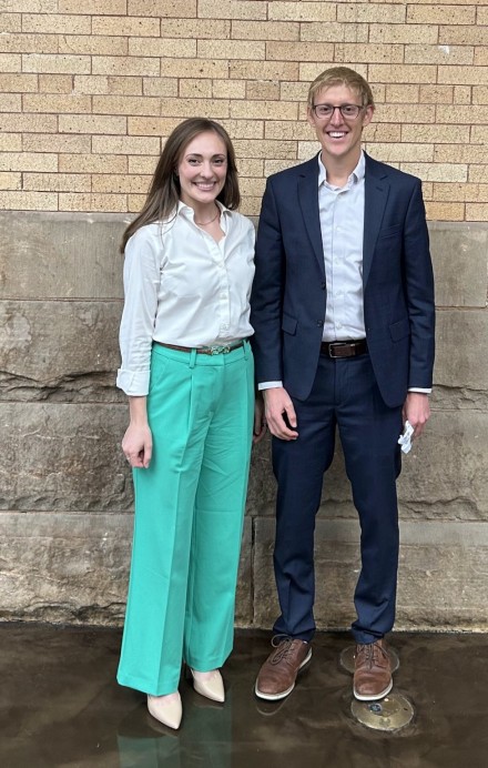 A man and woman stand in front of a brick wall posing for a picture