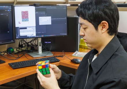 Man sitting at a desk solving a Rubik's cube