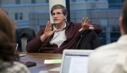 Man seated at table gesturing with both hands