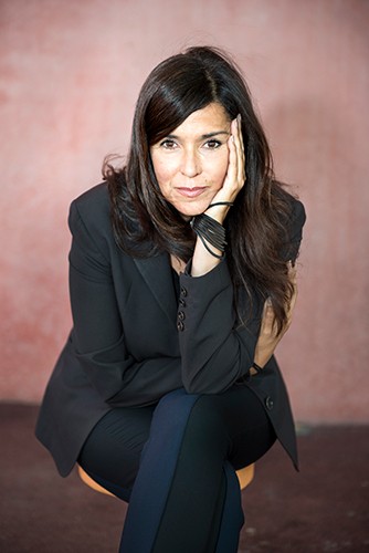 Woman in black jacket sitting with hand against her face