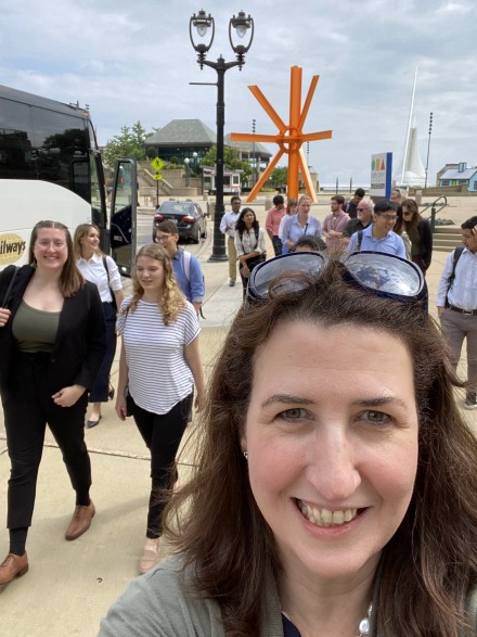 Woman smiling for selfie with students in the background