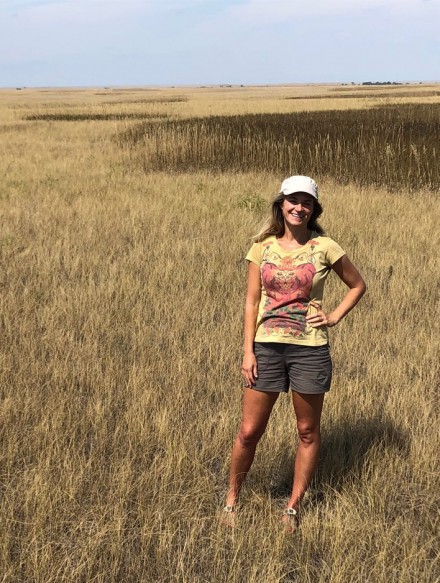 Holly Gibbs stands in a field of brownish grass