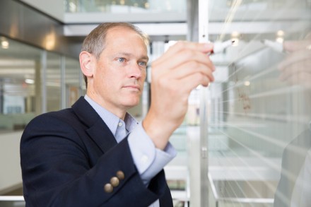 Man in sport coat writing on whiteboard