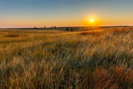 The sun sets over a prairie