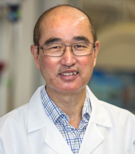 Asian man with glasses and white lab coat posing for photo