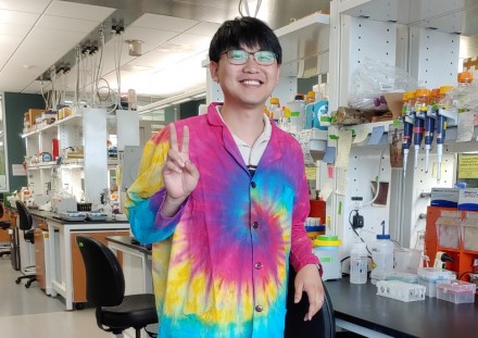 Sae-Byuk Lee poses for a photo at his lab bench in the Wisconsin Energy Institute