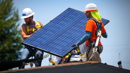 Workers from GRID Alternatives, a San Diego nonprofit that provides no- or low-cost rooftop solar to low-income families, install a solar panel at a home in 2017.