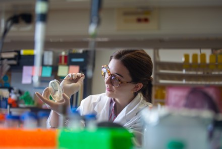 woman in lab coats examines petri dish