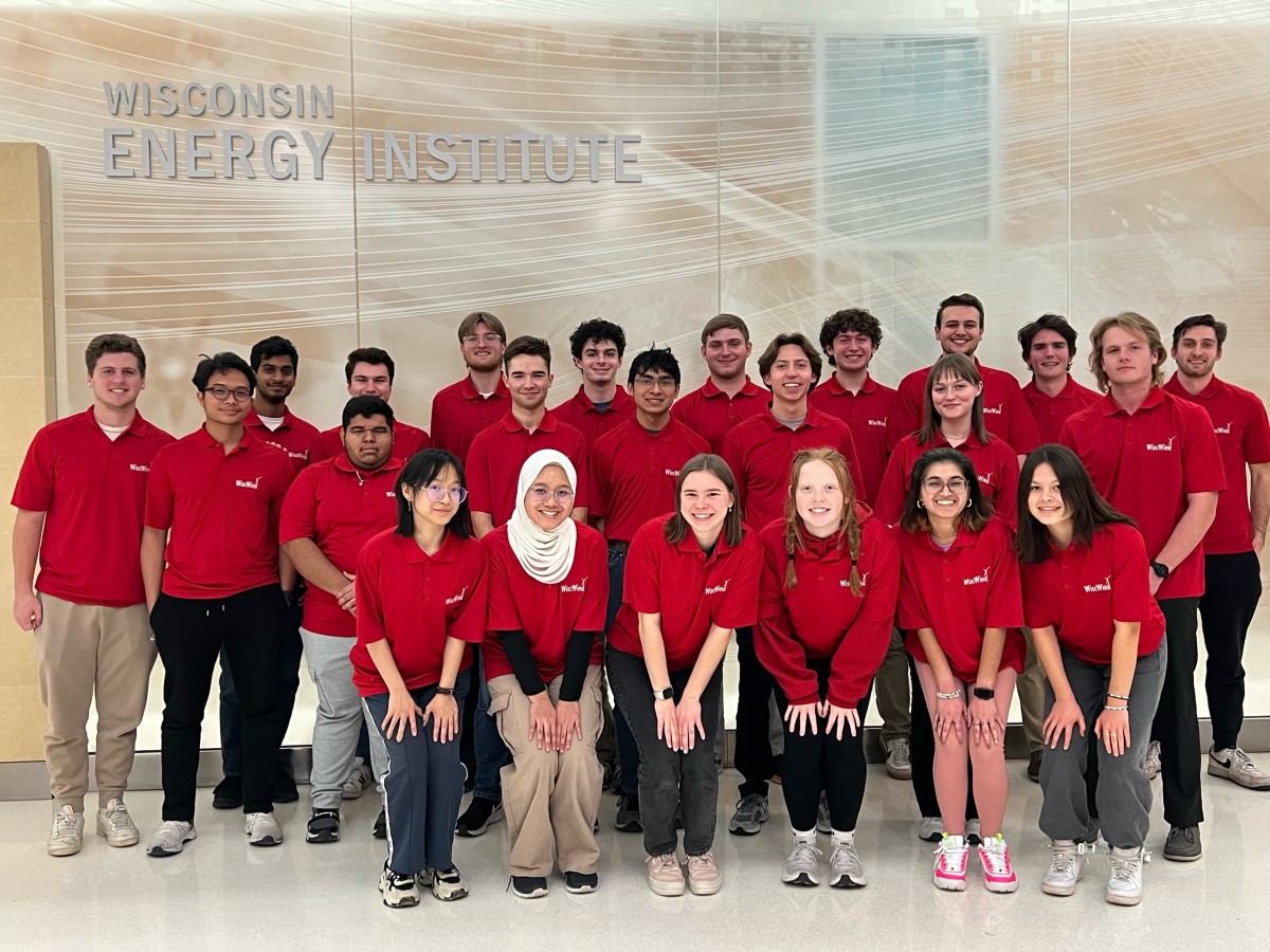 Twenty-three WiscWind team members clad in red pose for a picture in the lobby of the Wisconsin Energy Institute.