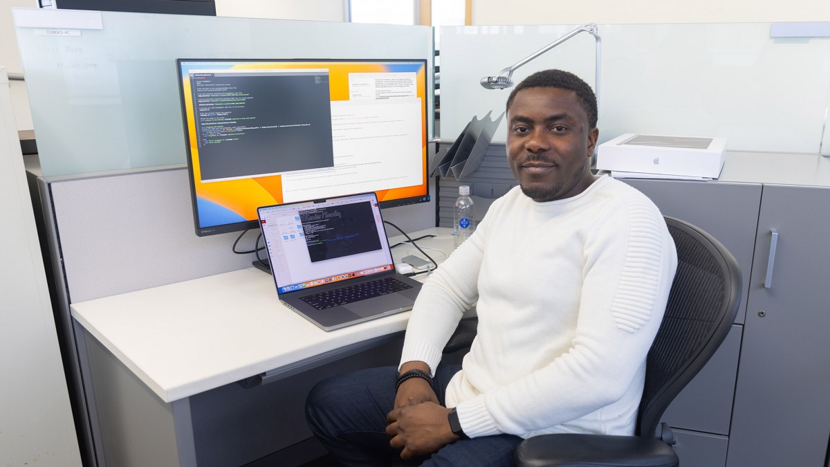 Blaise Manga Enuh sits at his desk in front of a computer