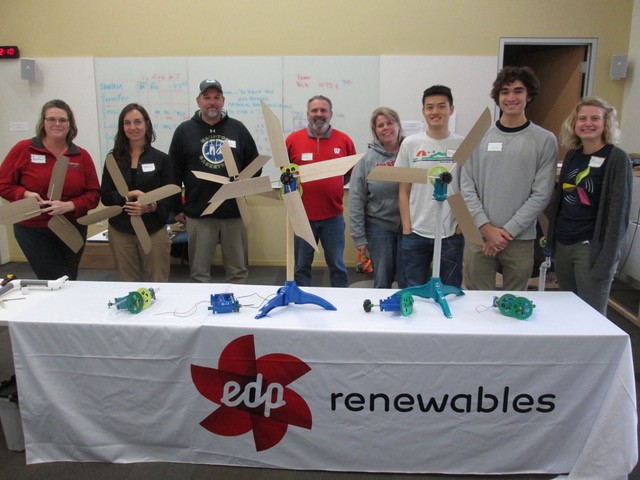 Educators pose for a photo during a previous KidWind Workshop. They show off their turbines and stand behind an EDP Renewables banner.
