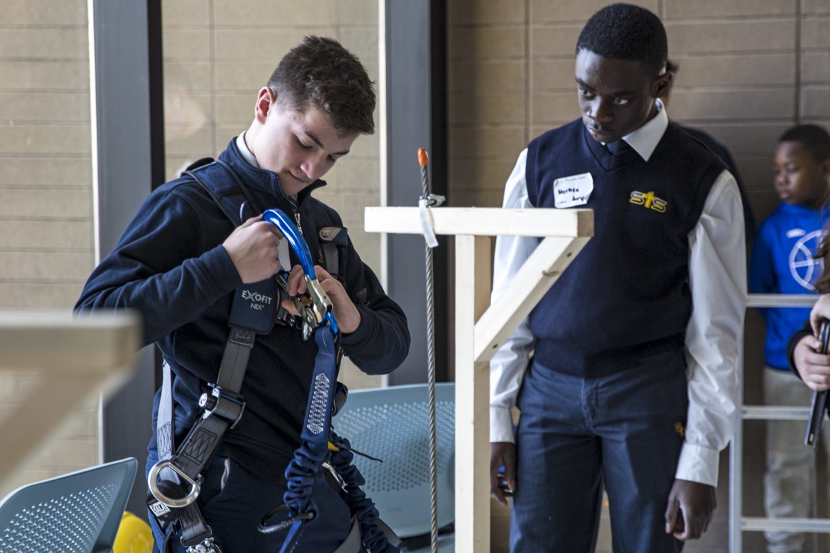 Two students put on climbing gear during a relay race