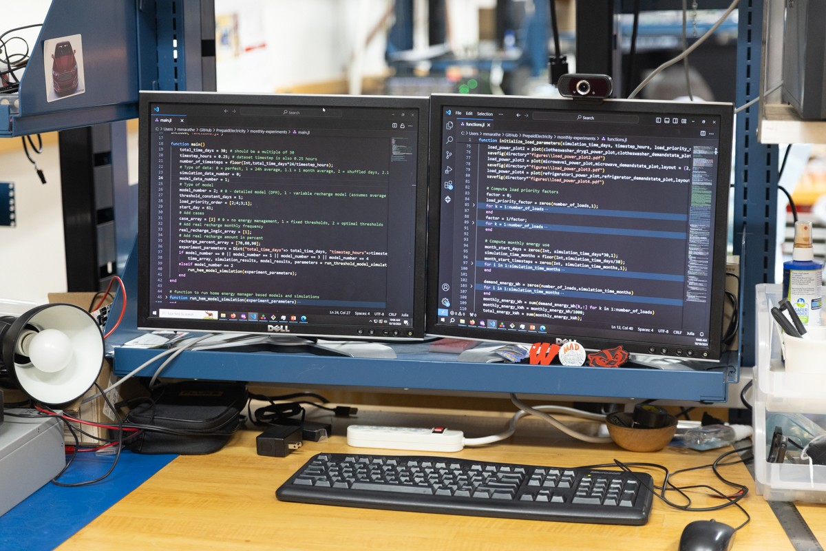 A pair of computer monitors on a workbench display lines of code