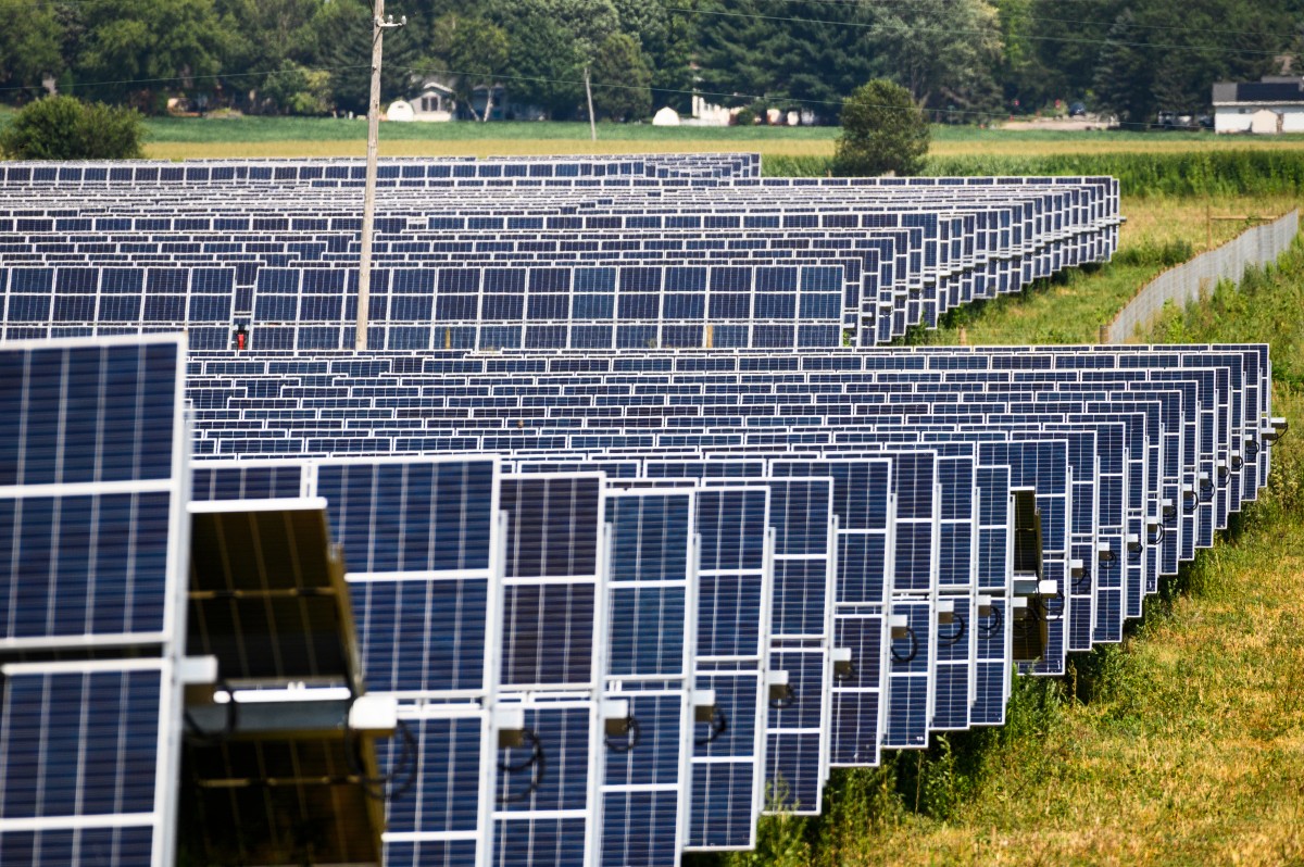 The image depicts rows and rows of solar panels in a 140-acre solar field.