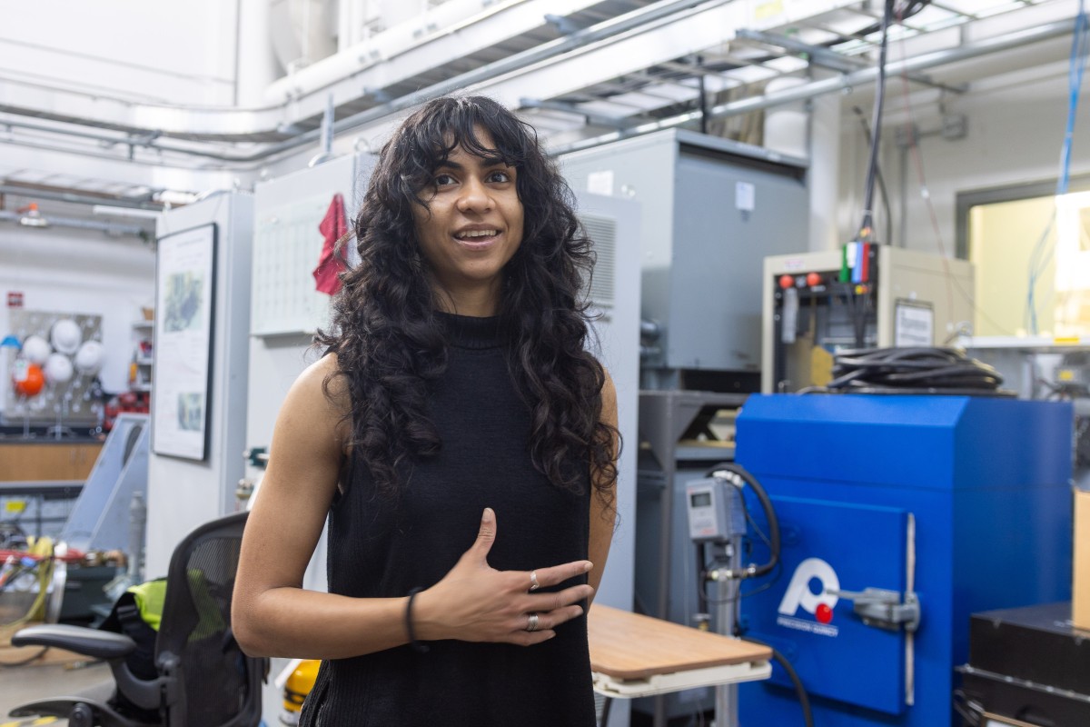 Woman with long black hair gesturing and talking in an electronics laboratory