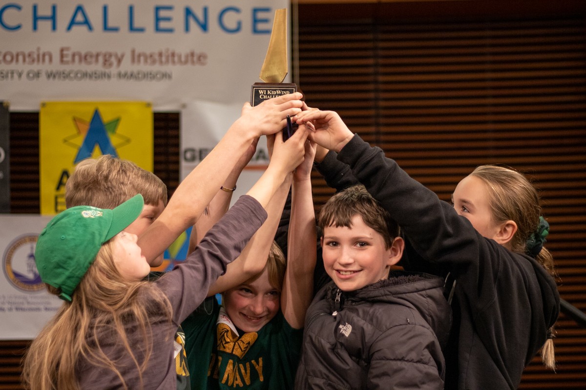 A team of students lift their trophy high into the air.