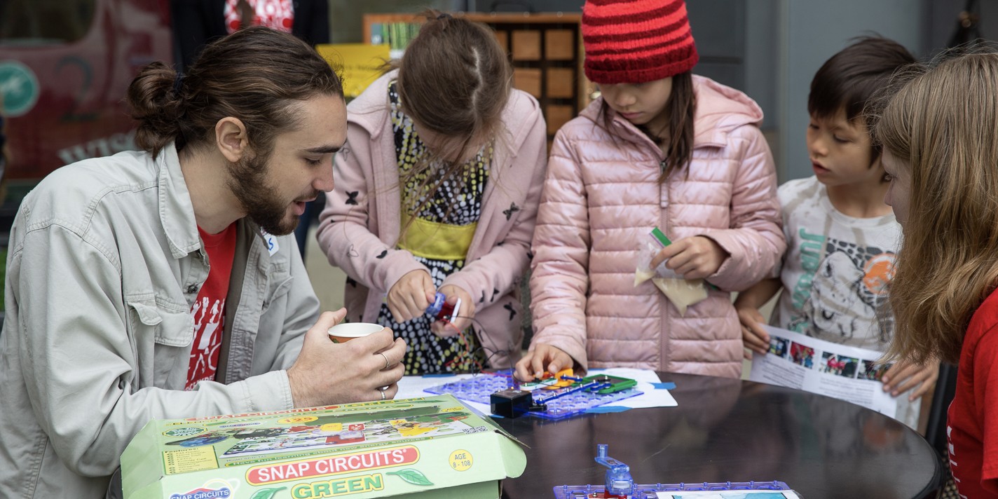 Children gather around a table to build a solar powered circuit at Family Gardening Day 2023..