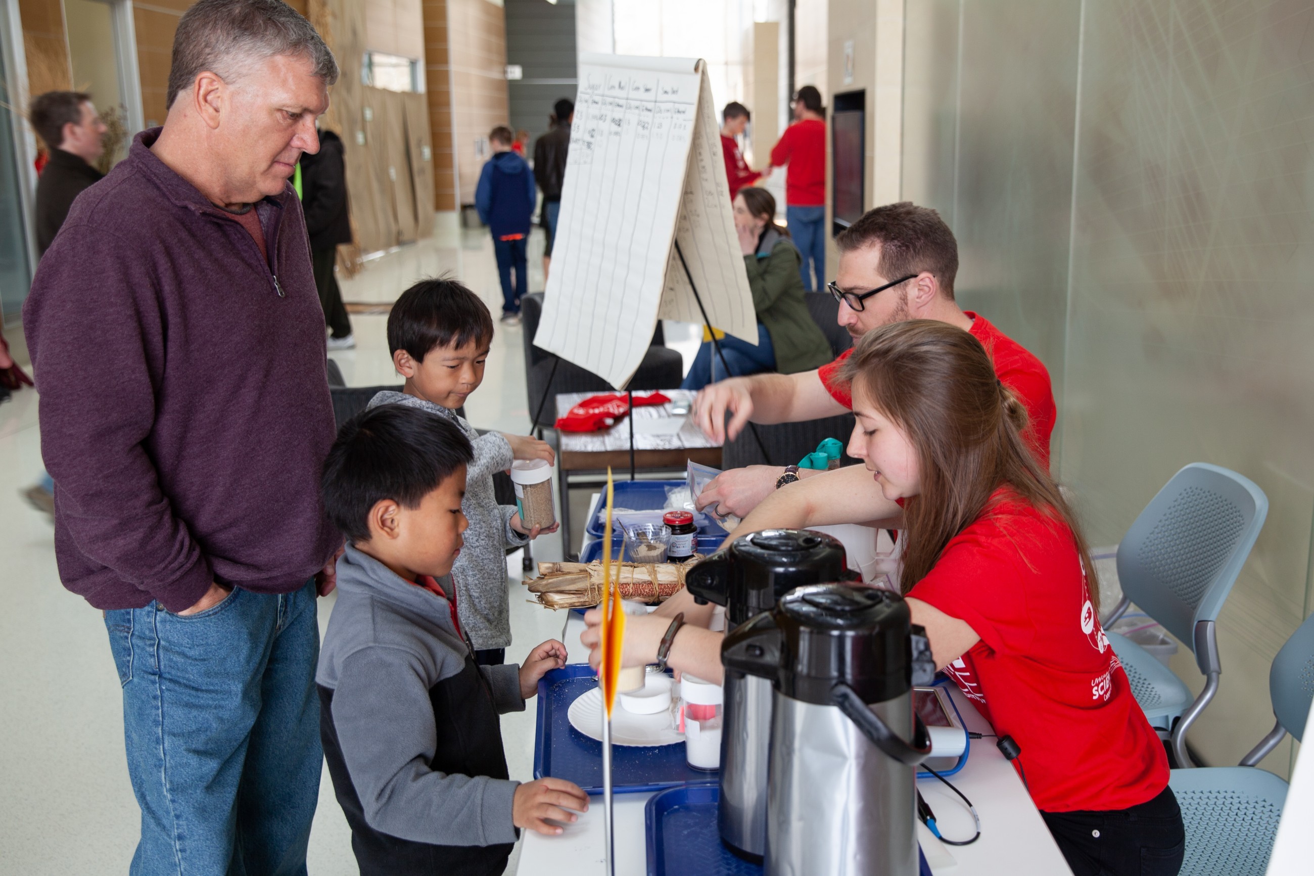 Two kids mix sugar and cornmeal with water and yeast in a fermentation experiment.