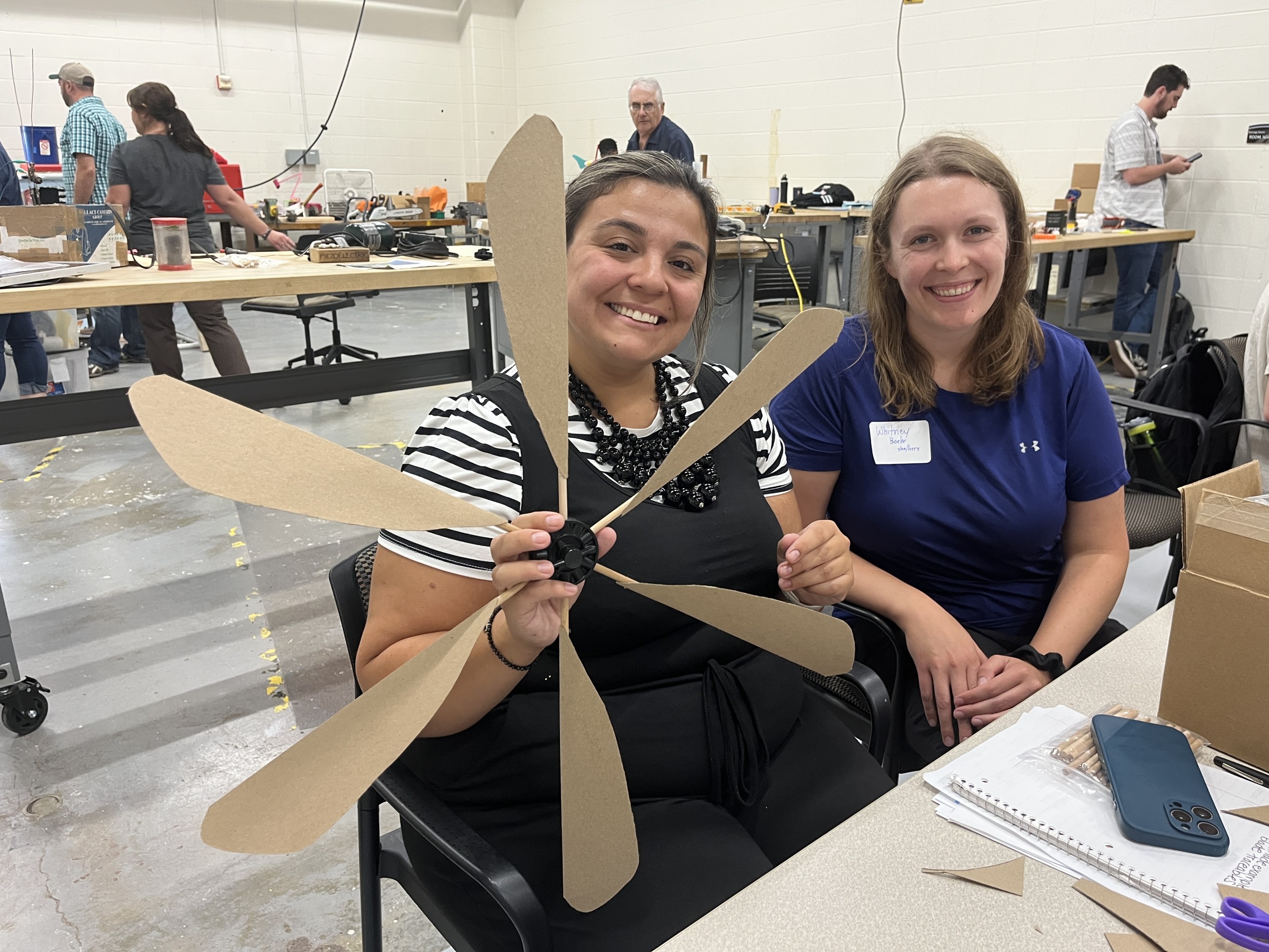 Teachers smile holding their wind turbine rotor at a previous KidWind workshop.