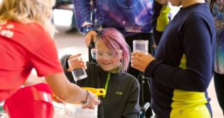 A young student pours water through a strainer while demonstrating the Plastic Panic activity