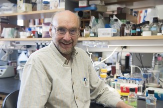 Smiling man seated at lab bench turning to face camera