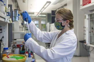 Leta Landucci pipettes while working in her lab coat