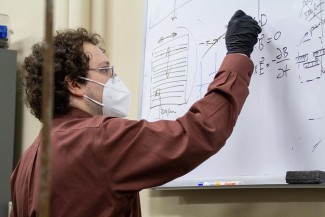 Mikhail Kats writes on a whiteboard in his lab