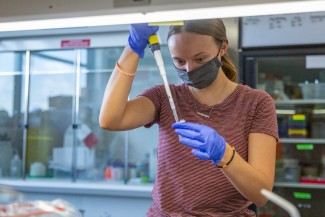 Megan Mader stands a lab bench using a pippette