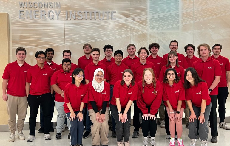 Twenty-three WiscWind team members clad in red pose for a picture in the lobby of the Wisconsin Energy Institute.