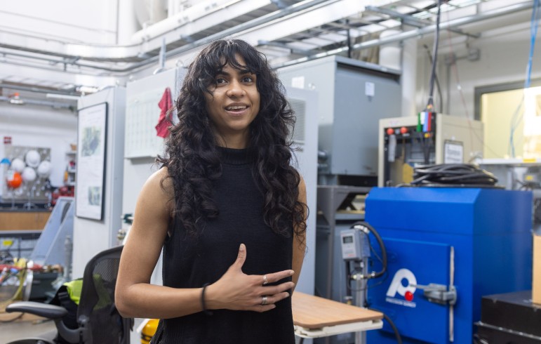Woman with long black hair gesturing and talking in an electronics laboratory