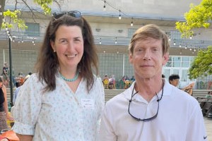 Man and woman smiling for photo in a sunny outdoor location