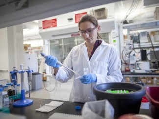 Woman in white lab coat and blue gloves working in a laboratory