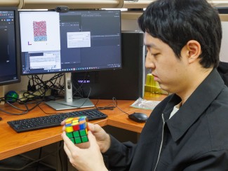 Man sitting at a desk solving a Rubik's cube