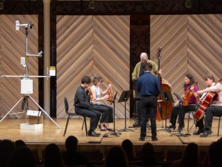 musicians on a stage next to weather monitoring equipment