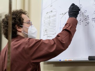 Mikhail Kats writes on a whiteboard in his lab