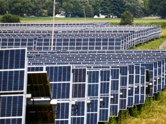 The image depicts rows and rows of solar panels in a 140-acre solar field. 