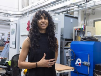Woman with long black hair gesturing and talking in an electronics laboratory
