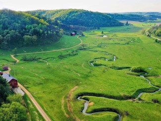 Aerial photo of green pasture with winding stream
