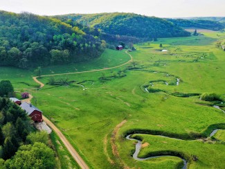 Aerial photo of green pasture with winding stream