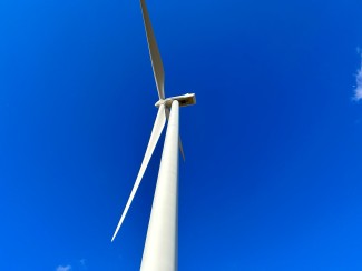 White wind turbine seen from below against clear blue sky