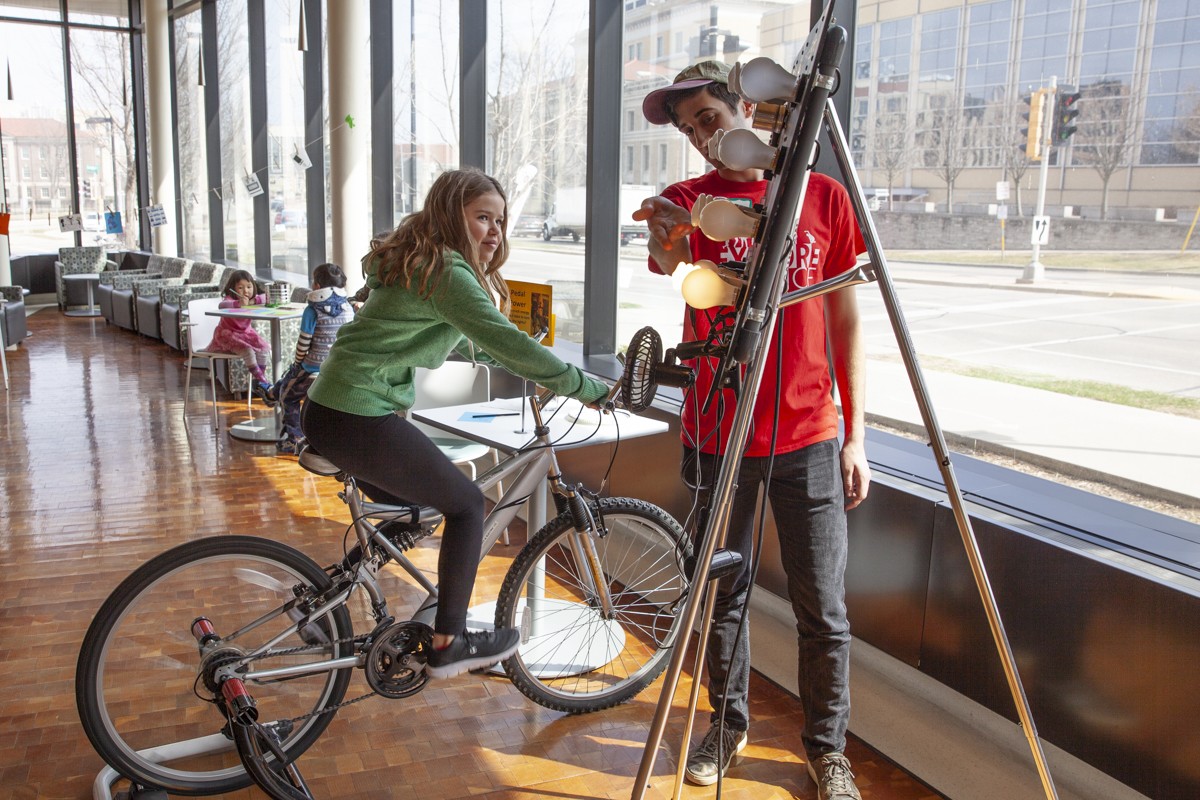 Participants pedals a bike to see how many lightbulbs they can power.