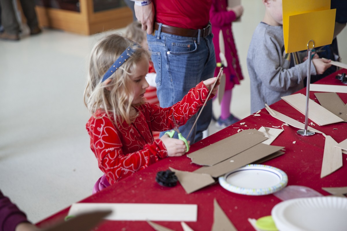 Young participant glues cardboard to a wooden dowell to make a turbine blade.